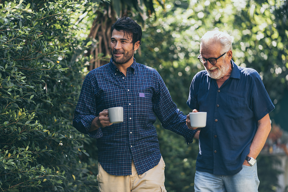 Father-son bonding. Cheerful young man drinking coffee together with him